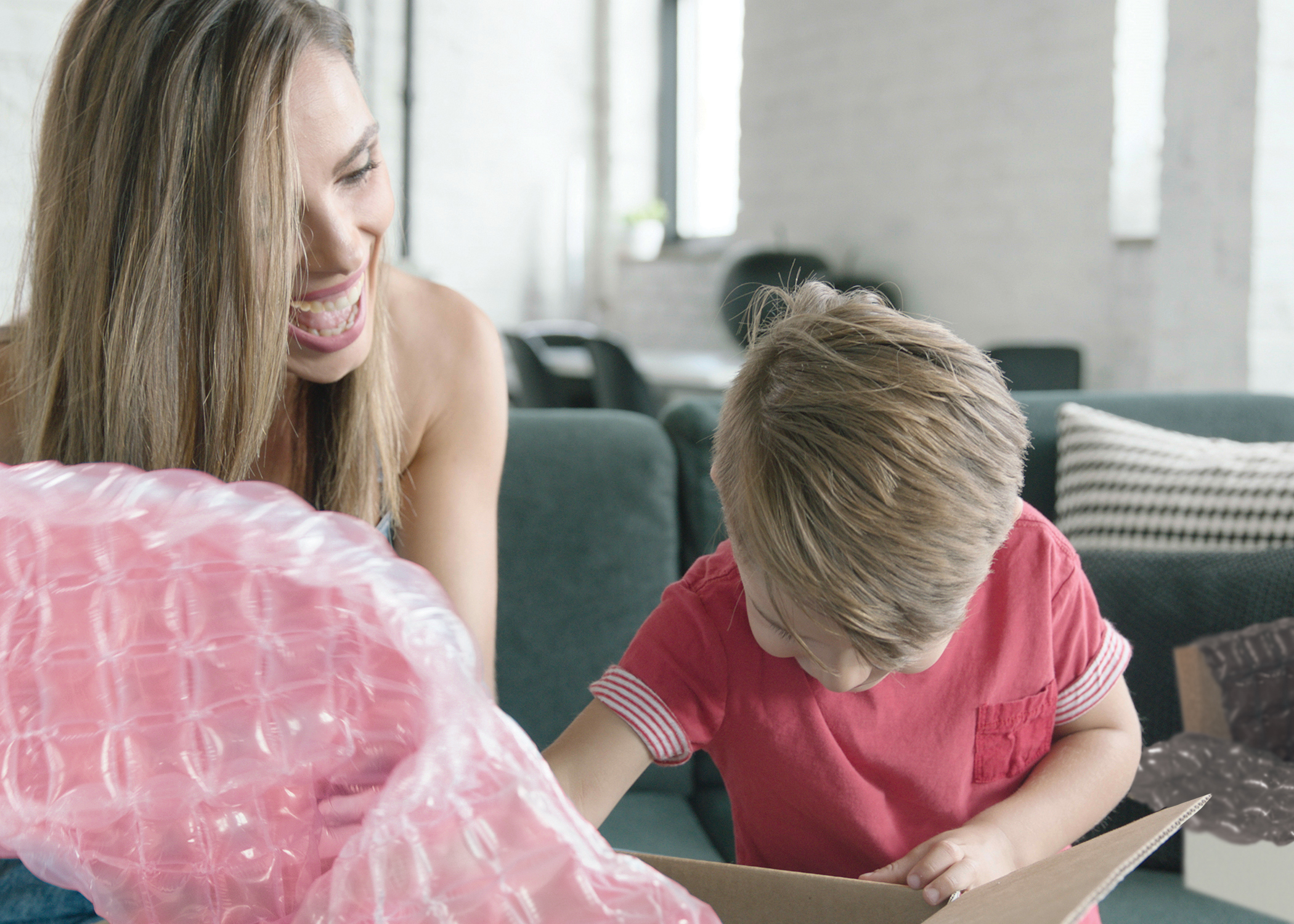 Mother happily opening package with son containing package protected by Inspire Pink Protective Packaging